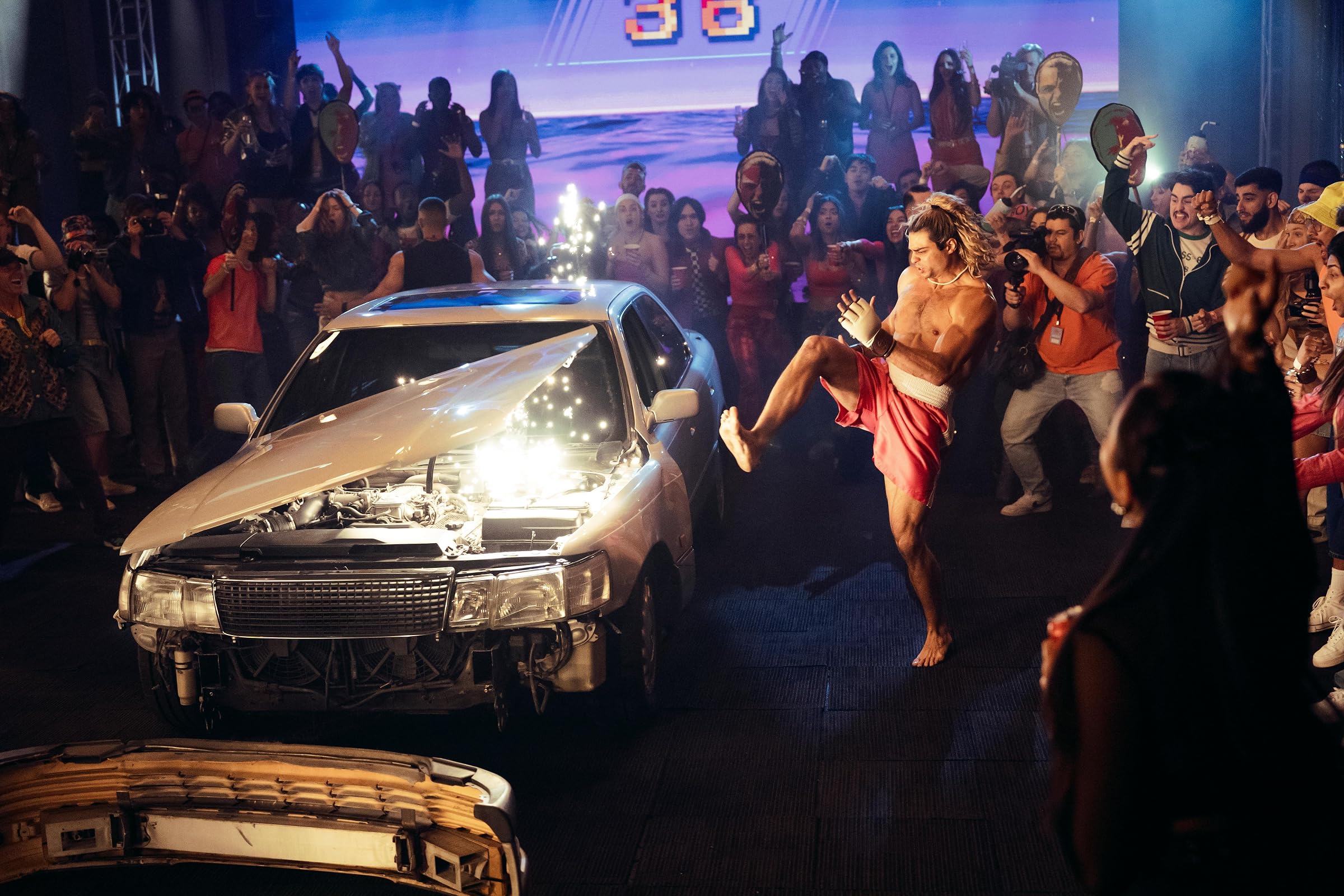 Escena de Street Fighter con una multitud alrededor de un auto en una calle de noche