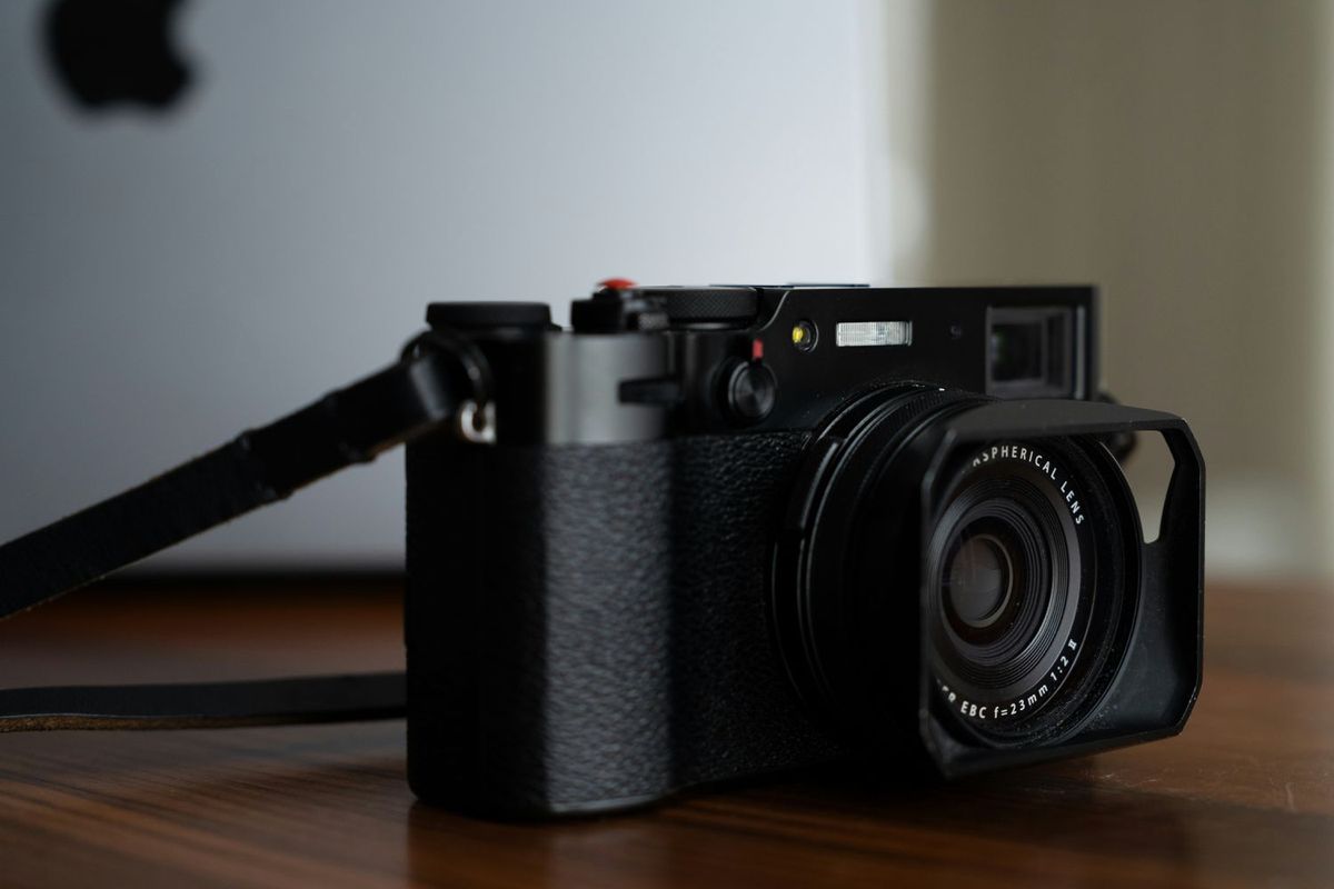 Una Fujifilm X100VI plateada sobre una mesa de madera, con luz lateral